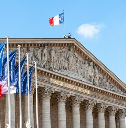 La facciata dell'Assemblea Nazionale francese, adornata da bandiere e intricate sculture.